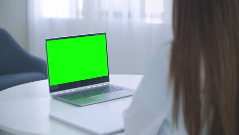 Woman-doctor-is-consulting-online-laptop-with-green-screen-on-table-chroma-key-concept